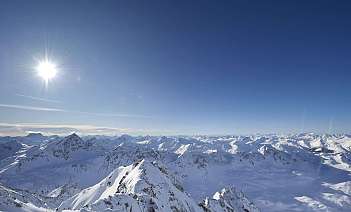 Snowy mountain landscape Panoramic view of snow-covered mountains under a clear blue sky.