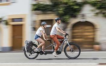 Paar fährt auf einem Fahrrad Ein Paar fährt auf einem Tandemfahrrad durch eine Stadt.