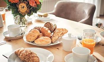 Breakfast table with pastries A table set with various pastries, drinks, and flowers.