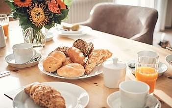 Frühstückstisch mit Gebäck Ein gedeckter Tisch mit verschiedenen Brötchen und Blumen.