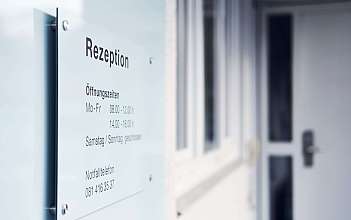 Rezeption mit Öffnungszeiten Schild mit Öffnungszeiten der Rezeption und Notfallnummer.