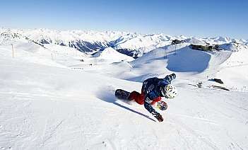 Un snowboarder dévalant une montagne sous un ciel bleu.