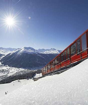 Rote Bergbahn mit schneebedeckten Bergen im Hintergrund.
