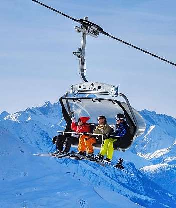 Group of skiers riding a chairlift in snowy mountains.