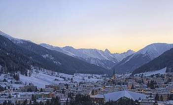 Snowy Mountain Village at Dusk A scenic view of a snow-covered village surrounded by mountains at sunset.