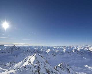 Paysage montagneux avec neige et ciel bleu ensoleillé.