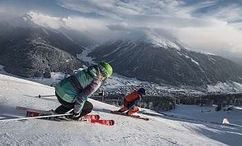 Two skiers navigating a snowy mountain slope with a scenic backdrop.