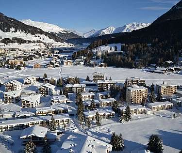 Vue aérienne d&#039;un village en hiver avec des montagnes enneigées.