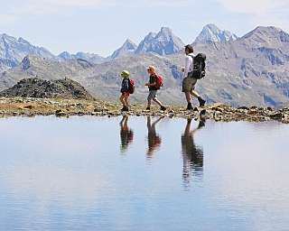 Trois randonneurs marchent près d&#039;un lac de montagne.
