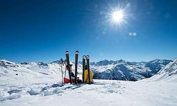 Two skiers resting on snow with mountains in the background.