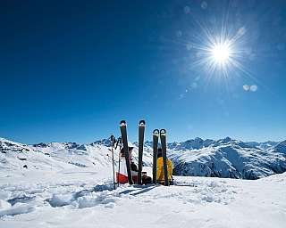 Two skiers resting on snow with mountains in the background.