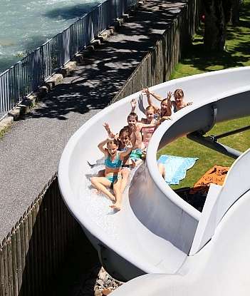 Group of children enjoying a water slide on a sunny day.