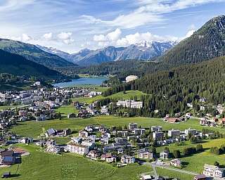 Village alpin entouré de montagnes et de verdure.