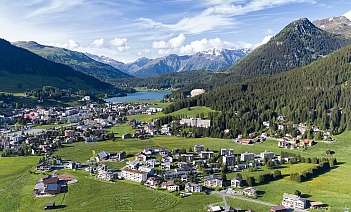 Landschaft mit Bergen und Stadt Panoramaansicht einer Stadt umgeben von Bergen und Wäldern.