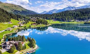 Vue panoramique d&#039;un lac avec des maisons et des montagnes en arrière-plan.