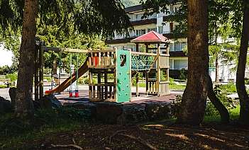 Spielplatz mit Rutsche und Klettergerüst Holzspielplatz mit Rutsche, Kletterwand und Schaukeln im Freien.