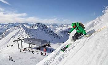 Skifahrer auf schneebedecktem Berg Ein Skifahrer fährt auf einer Piste mit Bergpanorama.