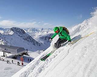 Un skieur dévale une montagne avec des paysages alpins en arrière-plan.