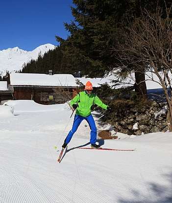 Ein Skifahrer gleitet durch eine verschneite Landschaft mit Hütten.