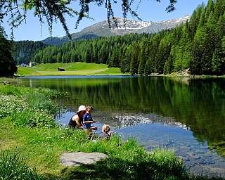 Une famille joue au bord d&#039;un lac entouré de verdure.