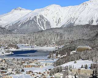 Schneebedeckte Berge über einem Winterort mit See und Wald