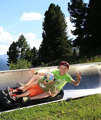 Two children enjoying a slide with mountains in the background.