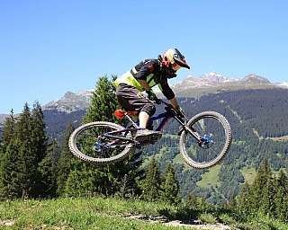 Ein Mountainbiker springt mit Blick auf die Berge.