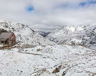 Un refuge en pierre dans un paysage montagneux enneigé.
