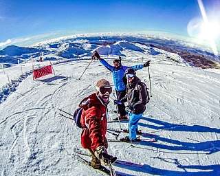 Drei Skifahrer posieren auf einem schneebedeckten Hang.