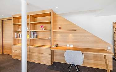 Ein minimalistisches Arbeitszimmer mit Holzregalen und einem Schreibtisch.