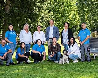 Groupe de personnes posant ensemble dans un parc avec un chien.