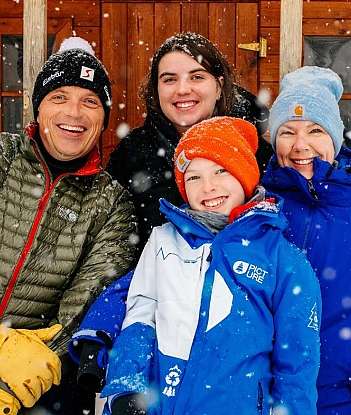 Quatre personnes souriantes devant un chalet enneigé.