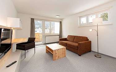Gemütliches Wohnzimmer mit Sofa, Tisch und Fernseher.
