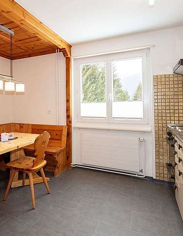 Helle Küche mit Holzdetails und Essplatz am Fenster.