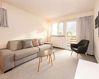 Gemütliches Wohnzimmer mit Sofa, Tisch und Blick auf die Berge.