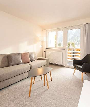 Gemütliches Wohnzimmer mit Sofa, Tisch und Blick auf die Berge.