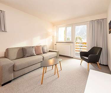 Bright living room with sofa, chair, and balcony access.