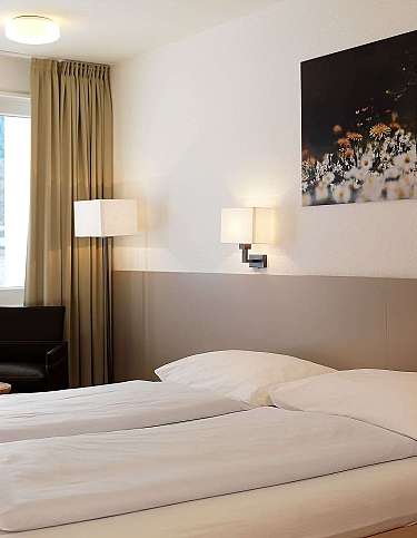Gemütliches Schlafzimmer mit zwei Betten und Fensterblick.