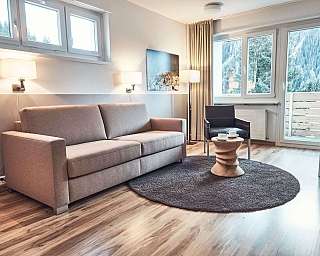 Modernes Wohnzimmer mit Sofa, Stühlen und Blick auf die Berge.