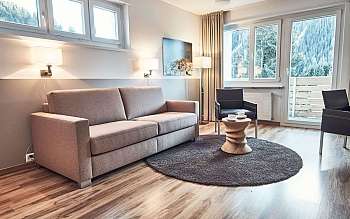 Un salon avec un canapé, des chaises et une vue sur la nature.