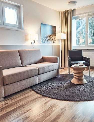 Modernes Wohnzimmer mit Sofa, Stühlen und Blick auf die Berge.