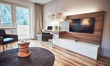 Modernes Wohnzimmer mit Balkon Helles Wohnzimmer mit Fernseher, Schreibtisch und Balkonblick.