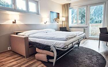 Helles Schlafzimmer mit einem Bett, Stühlen und Blick auf die Berge.