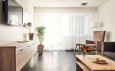 Gemütliches Wohnzimmer mit Pflanzen, TV und Tisch mit Snacks.