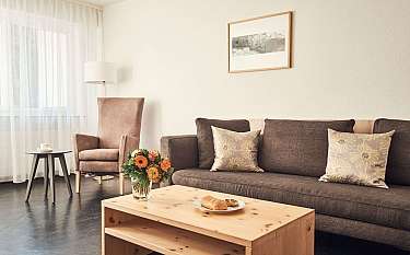 Gemütliches Wohnzimmer mit Sofa, Blumen und einem Tisch.