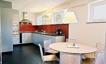Moderne Küche mit Esstisch Helle Küche mit roter Fliesenwand und runden Esstisch.