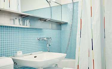 Modernes Badezimmer mit Waschbecken, Dusche und buntem Vorhang.