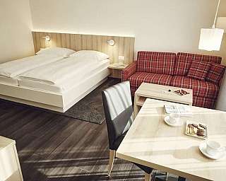 Modernes Hotelzimmer mit Doppelbett, Couch und Tisch.