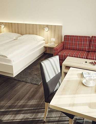 Modernes Hotelzimmer mit Doppelbett und gemütlicher Couch.