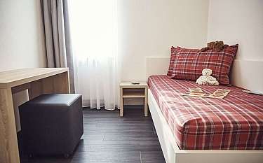 Ein einfaches Schlafzimmer mit einem Bett, Schreibtisch und Fenster.